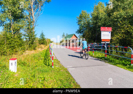 CZARNY DUNAJEC, POLAND - SEP 12, 2018: Young woman riding bike on cycling track around Tatra Mountains near Czarny Dunajec village. The end point is i Stock Photo