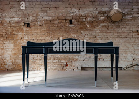 Black wooden console table against the old brick wall background in workshop Stock Photo