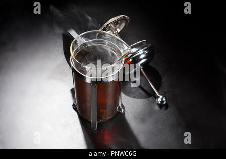 Smoke from hot tea in the tea press container, viewed from above. Stock Photo