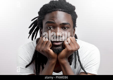 unhappy serious young African American with dreadlocks rests head on hands Stock Photo