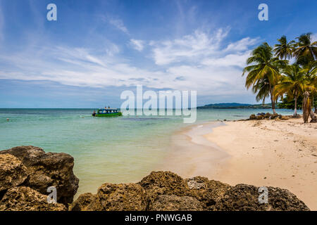 Amazing tropical beach in Caribe, boat with tourists, palm trees, white sand beach - Trinidad and Tobago Stock Photo