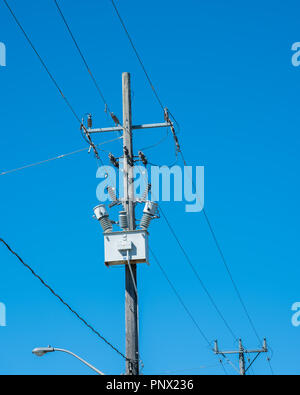 High voltage wires and a transformer box against a clear essential services, service, blue sky with copy space. Stock Photo