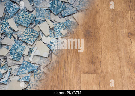 Retro ceramic tiles and modern vinyl texture. Floor renovation concept. Contrast of shards from a broken old facing and new wooden flooring background. Stock Photo