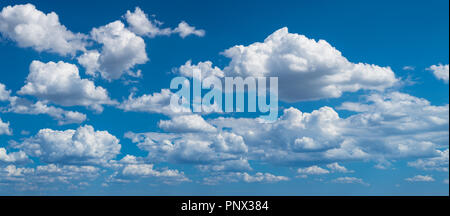 Romantic panoramic cloudscape with azure blue heaven. Idyllic sunlit panorama with flowing white fluffy clouds. Beautiful clear sky in background. Stock Photo