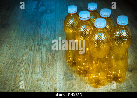 Empty PET bottles on wood background. Ecological separation of household garbage. Orange used packages with white caps on floor. Plastic waste sorting. Stock Photo