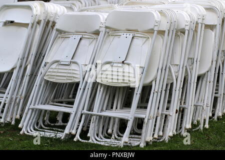 The white chairs are stacked up before the wedding. Stock Photo