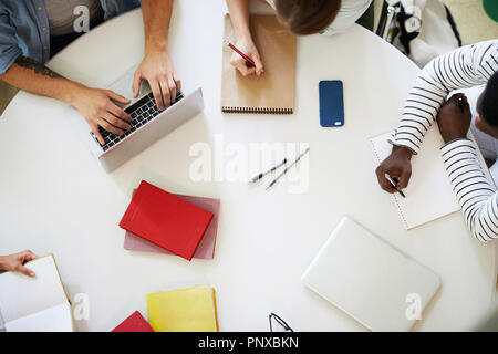 Overview of hands of students sitting around table, brainstorming and preparing for project Stock Photo