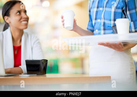 One of businesswomen taking drinks and boxes with chinese food off white plastic tray while putting them on table Stock Photo