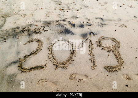 2019 written on the sea sand with foot prints.  Natural sand textured background. New year and travel plans  coming soon concept Stock Photo