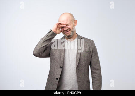 Mature bald man in suit with a problem is crying. Negative facial emotion Stock Photo