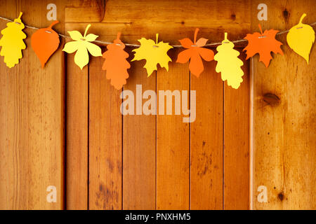 Simple, rustic country style Thanksgiving home decorations paper crafts garland banner colorful fall leaves on wood background Stock Photo