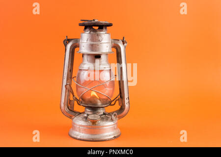 Old retro gas lantern with burning light isolated on orange background. Lamp in studio. Empty space for text Stock Photo