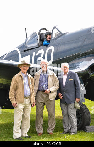 Veteran Corsair pilots Keith Quilter, Christopher Cartledge & Peter George, with Stephen Grey in The Fighter Collection Goodyear Corsair fighter plane Stock Photo