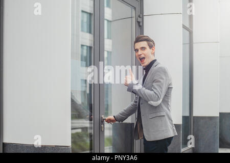 Close up of young business man opening door of modern business center. Stock Photo