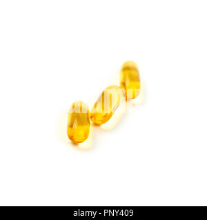 Close up three yellow Omega 3 vitamins and essential fish oils gel cap pills isolated on white background, high angle view Stock Photo