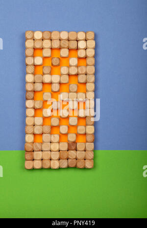 Close up wooden toy building blocks in shape of high rise tower house over green and blue color paper background for grass and sky with copy space Stock Photo