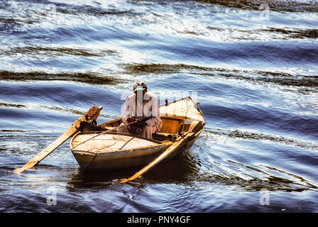 A small wooden fishing boat low in water with man fishing and boy rowing  surrounded by lightly broken water, Nile, Egypt, Africa Stock Photo - Alamy