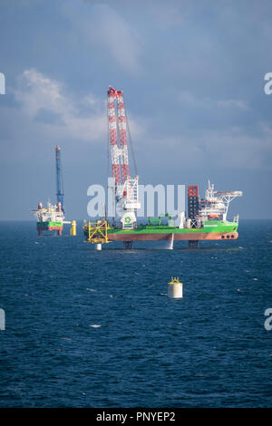 The jack up construction vessels, Sea Installer (left) and Innovation (right) installing transition pieces and foundations in preparation for turbine installation on Hornsea Project One Offshore Wind Farm. Stock Photo