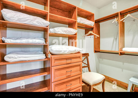 Walk-in closet with built in shelves, clothes rails and drawers. Stock Photo