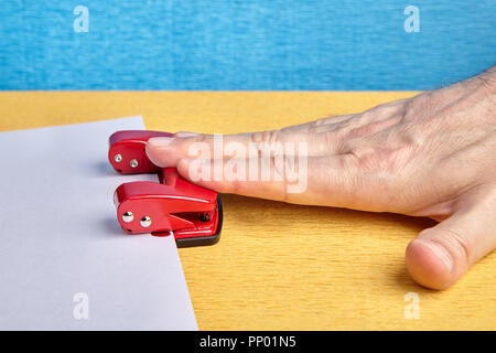 Close-up of hand presses spring office hole punch. Stock Photo