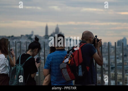 Tourists enjoying the view from Arc de Triomphe rooftop, with Basilique du Sacré-Cœur in the background