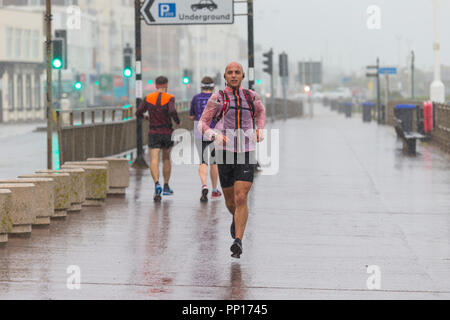 Hastings, East Sussex, UK. 23rd Sep, 2018. UK Weather: Heavy rain and driving wind in the seaside town of Hastings this morning, temperatures have dropped below 13°C. These joggers brave the wet and windy conditions running along the promenade. © Paul Lawrenson 2018, Photo Credit: Paul Lawrenson / Alamy Live News Stock Photo