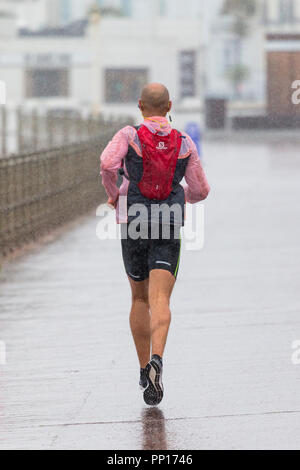 Hastings, East Sussex, UK. 23rd Sep, 2018. UK Weather: Heavy rain and driving wind in the seaside town of Hastings this morning, temperatures have dropped below 13°C. These joggers brave the wet and windy conditions running along the promenade. © Paul Lawrenson 2018, Photo Credit: Paul Lawrenson / Alamy Live News Stock Photo