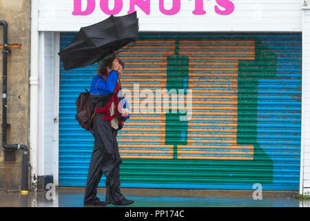 Hastings, East Sussex, UK. 23rd Sep, 2018. UK Weather: Heavy rain and driving wind in the seaside town of Hastings this morning, temperatures have dropped below 13°C. This man nearly loses his umbrella as a gust of wind turns it inside out. © Paul Lawrenson 2018, Photo Credit: Paul Lawrenson / Alamy Live News Stock Photo