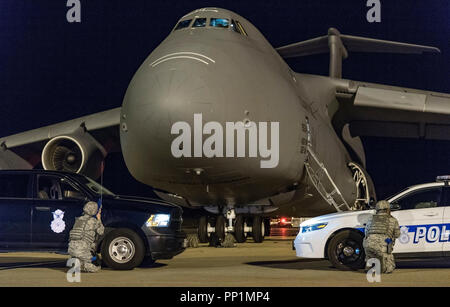 Two 436th Security Forces Squadron response force members take cover behind their vehicles positioned in front of a C-5M Super Galaxy as part of anti-hijacking measures Sept. 17, 2018, on Dover Air Force Base, Del. More than 20 response force members and other first responders positioned themselves and vehicles around the C-5M in response to a simulated attempted hijacking and hostage scenario. (U.S. Air Force photo by Roland Balik) Stock Photo