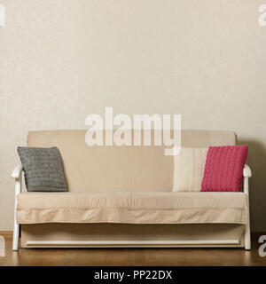 Beige sofa with colorful pillows (pink, grey, white) in the living room. Selective focus. Stock Photo