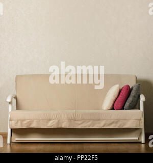 Beige sofa with colorful pillows (pink, grey, white) in the living room. Selective focus. Stock Photo