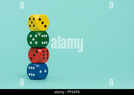 Colorful gaming dices stacked on a turquoise blue background Stock Photo