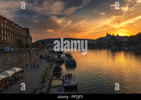 Prague, Czechia - September 19, 2018 : People walk along the Vltava river on the paved river bank known as Naplavka with boats, restaurants and views  Stock Photo