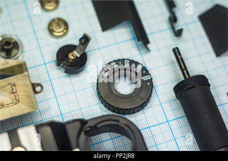 parts are completely disassembled old retro film SLR camera on graph paper, close-up Stock Photo