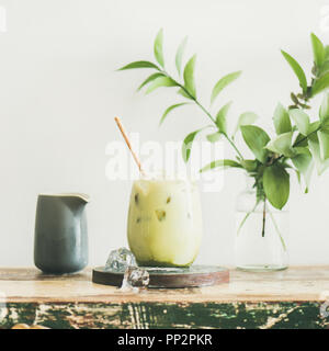 Iced matcha latte with milk pouring from pitcher, square crop