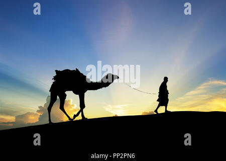 Walking with camel through Thar Desert in India, Show silhouette and dramatic sky Stock Photo