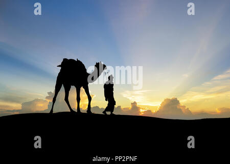 Walking with camel through Thar Desert in India, Show silhouette and dramatic sky Stock Photo