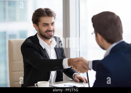 Smiling business partners shaking hands during meeting Stock Photo
