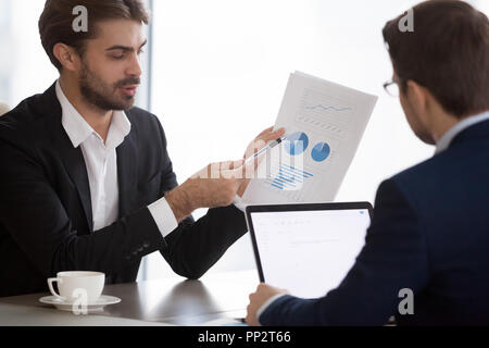 Male managers analyzing company financial statistics during meet Stock Photo
