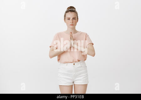 Girl studying martial arts, bowing to sensei. Serious, determined good-looking woman with freckles in trendy summer outfit, holding hands in pray, staring seriously at camera, greeting in asian style Stock Photo