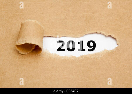 New year 2019 appearing behind ripped brown paper. Stock Photo