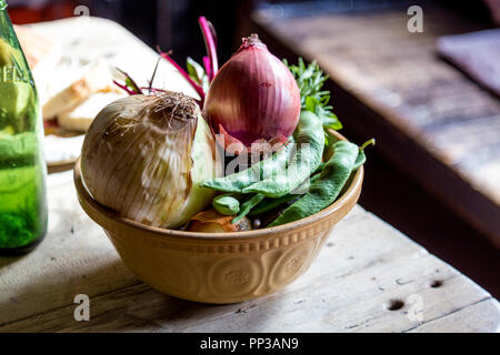 Rustic bowl of vegetables, onions and beans on a wooden table in an old-fashioned kitchen (Black Country Living Museum, Dudley, UK) Stock Photo