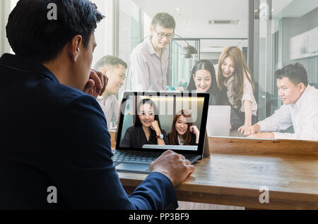 Businessman sitting and using computer laptop showing Group of asian Business team having video conference via monitor display in the modern conferenc Stock Photo