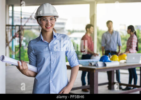 Portrait of Happy professional construction engineer woman holding the blueprint and wearing the safety helmet and glasses at the building site place  Stock Photo