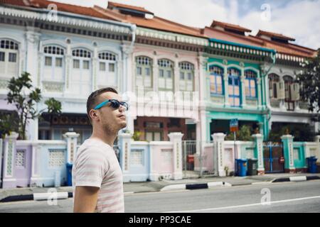 Tourist with sunglasses walking throught old street in Singapore. Colorful houses with combined Malay, Chinese, Indian and western architecture and cu Stock Photo
