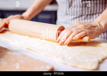 Close up of young womans hands on the rolling pin while cooking Stock Photo