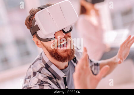 Handsome man in VR glasses trying to touch something Stock Photo