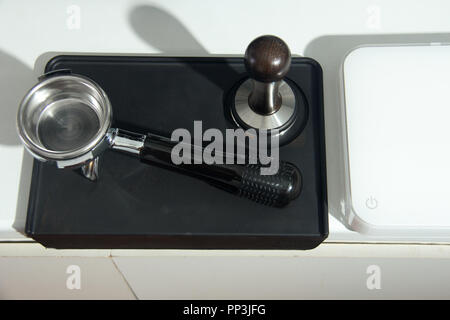 Man is using a tamper to press freshly ground morning coffee into a coffee tablet Stock Photo