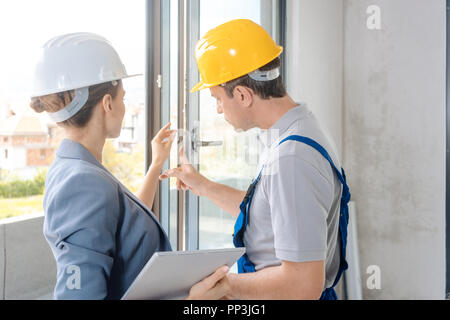 Architect and construction worker checking windows on site Stock Photo