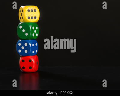 Colorful gaming dices stacked on a black background Stock Photo